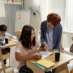 Humble Hac; Cute schoolgirl consulting with teacher during individual work