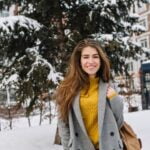 joyful smiling young Sandra Orlow, woman walking on street in city, cold winter weather