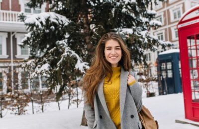joyful smiling young Sandra Orlow, woman walking on street in city, cold winter weather