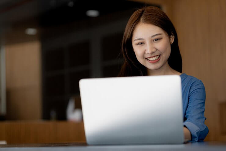 A Young Asian business woman working on laptop with a happy smile