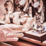 Close-up of the seller's hand in gloves shows the exclusive men's watch from the new collection in the luxury jewelry store