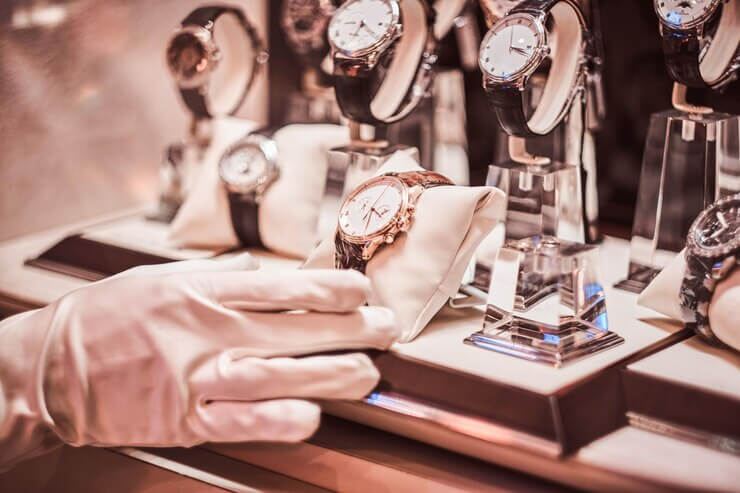 Close-up of the seller's hand in gloves shows the exclusive men's watch from the new collection in the luxury jewelry store