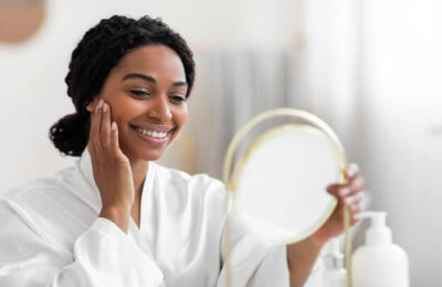 Attractive Black Woman Looking At Mirror And Touching Perfect Skin On Face