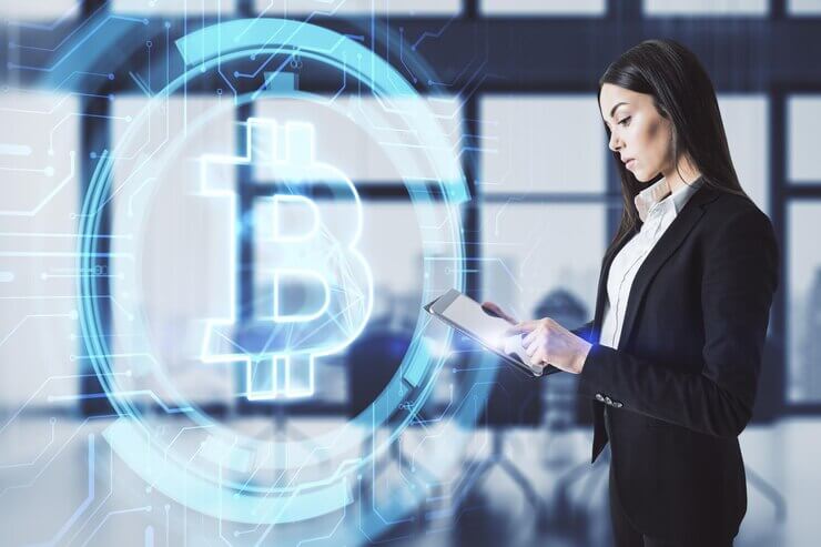 Attractive young european businesswoman using tablet with glowing bitcoin icon on blurry office interior background Cryptography money and investment concept Double exposure