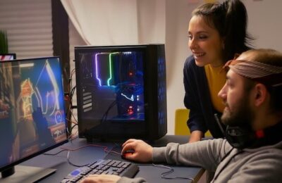 Pro gamer couple playing first person video game on powerful computer wearing professional headphones. Videogamer streaming gameplay cyber game sitting on gaming chair using RGB equipment