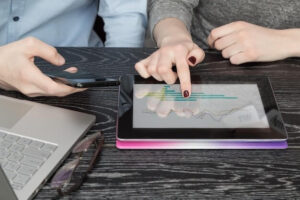 Midsection of colleagues using phones and digital tablet by laptop on desk