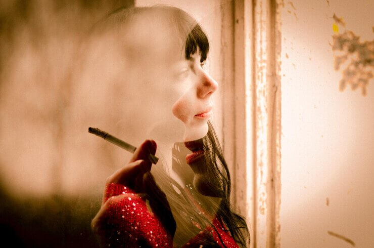 Portrait of young woman, cigarette in fingers, lost in thoughts