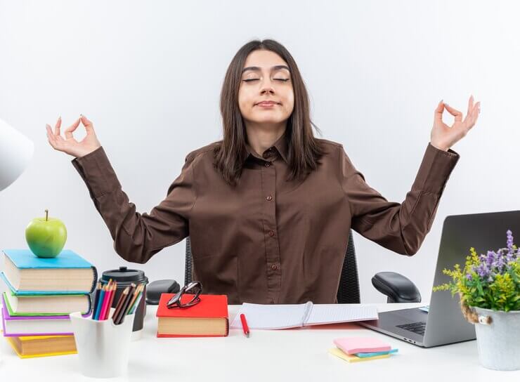 Stress Managementwoman sits at table with school tools doing meditation gesture