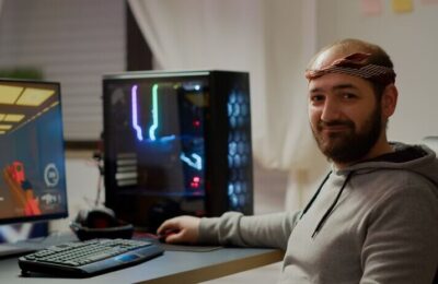 Professional esport man gamer looking at camera smiling while compete in videogame playing space shooter game. Online streaming cyber performing on powerful personal computer during gaming tournament