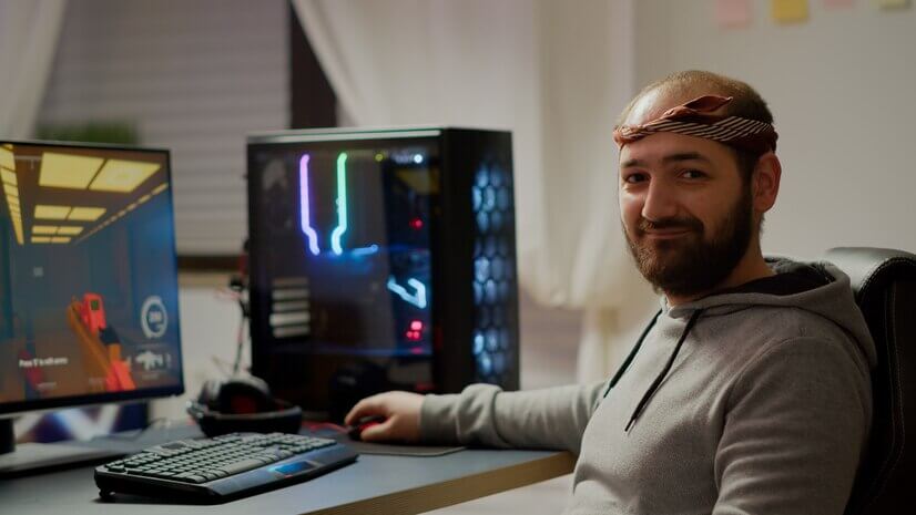 Professional esport man gamer looking at camera smiling while compete in videogame playing space shooter game. Online streaming cyber performing on powerful personal computer during gaming tournament