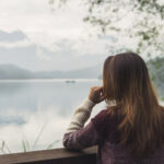 Lonely woman standing absent minded and looking at the river