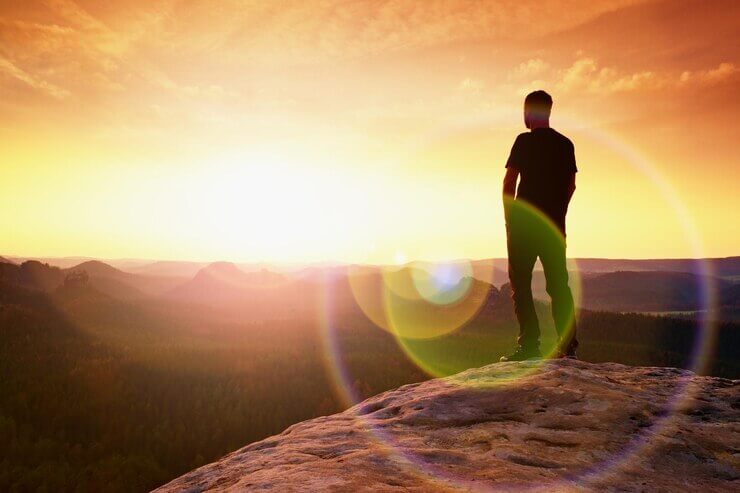 Thinking hiker in black on rocky peak wonderful daybreak ginger hair man in black at end of cliff