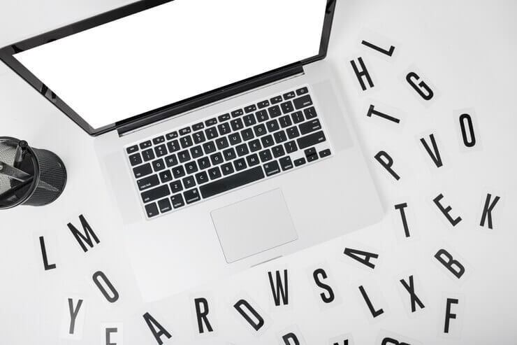 Elevated view of laptop with various alphabets on white background