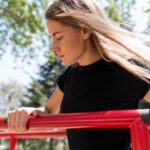 Woman holding herself on a metal bar