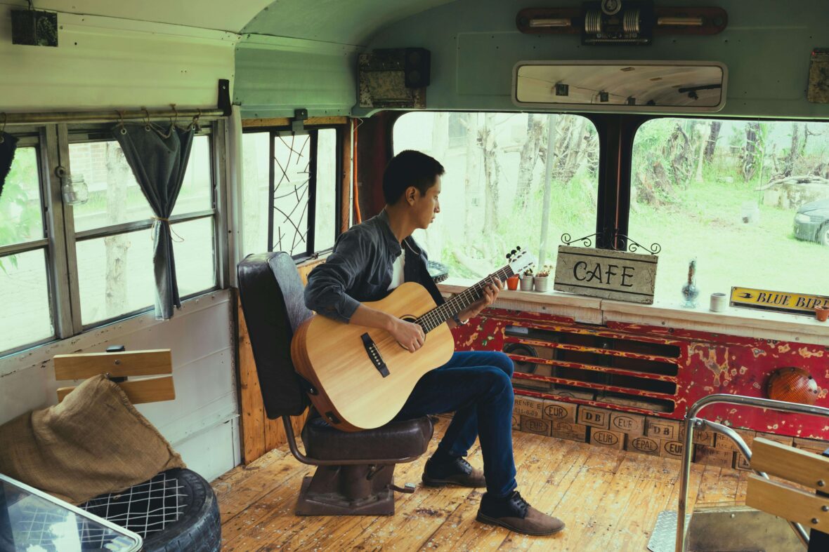 Man Playing Acoustic Guitar in Bus Turned into Cafe