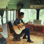 Man Playing Acoustic Guitar in Bus Turned into Cafe