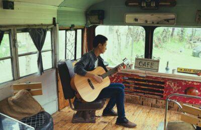 Man Playing Acoustic Guitar in Bus Turned into Cafe