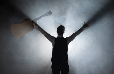 From behind shot of musician on stage holding a guitar