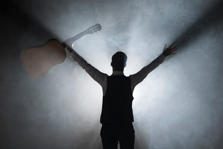 From behind shot of musician on stage holding a guitar