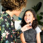 Woman In Black Floral Long Sleeve Shirt Holding A Bottle Of Essential Oil, talking with a young girl