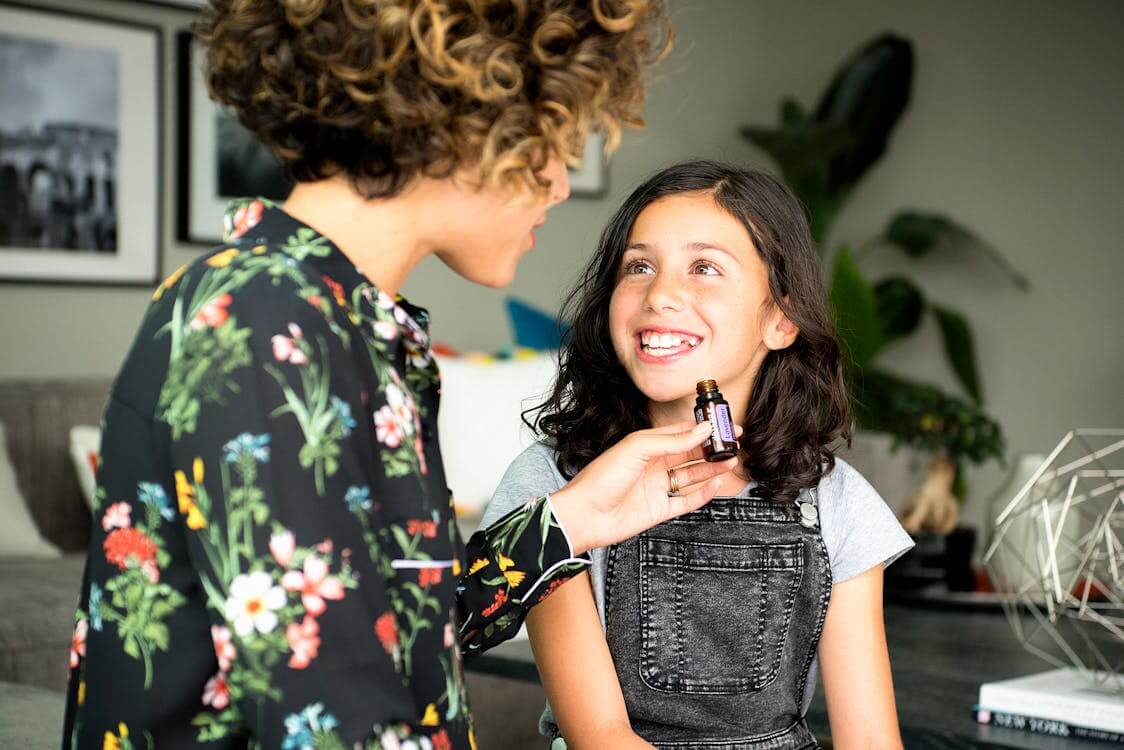 Woman In Black Floral Long Sleeve Shirt Holding A Bottle Of Essential Oil, talking with a young girl