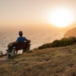 A Person Sitting on a Wooden Bench Looking at the Sunset