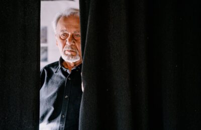 An Elderly Man Behind the Black Curtain