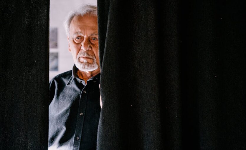 An Elderly Man Behind the Black Curtain