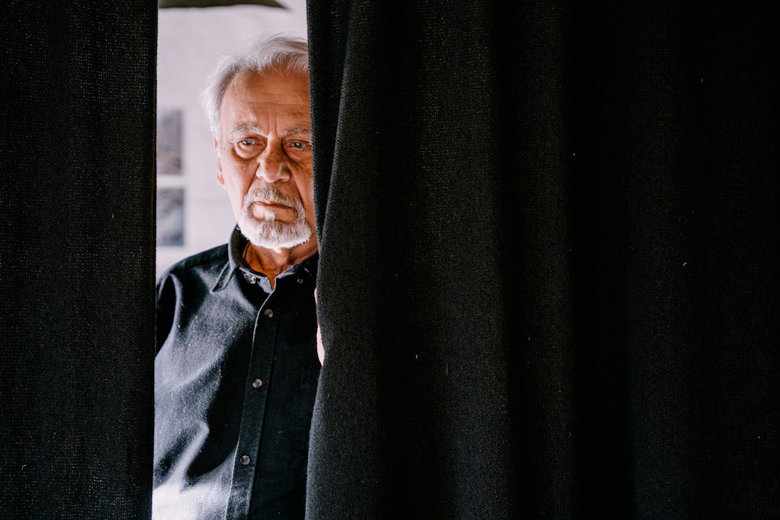 An Elderly Man Behind the Black Curtain