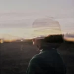 Woman Silhouette behind Window in Village at Sunset