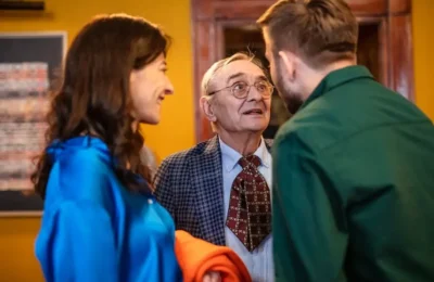 Photo of an Elderly Man in Glasses Talking to Two Young People