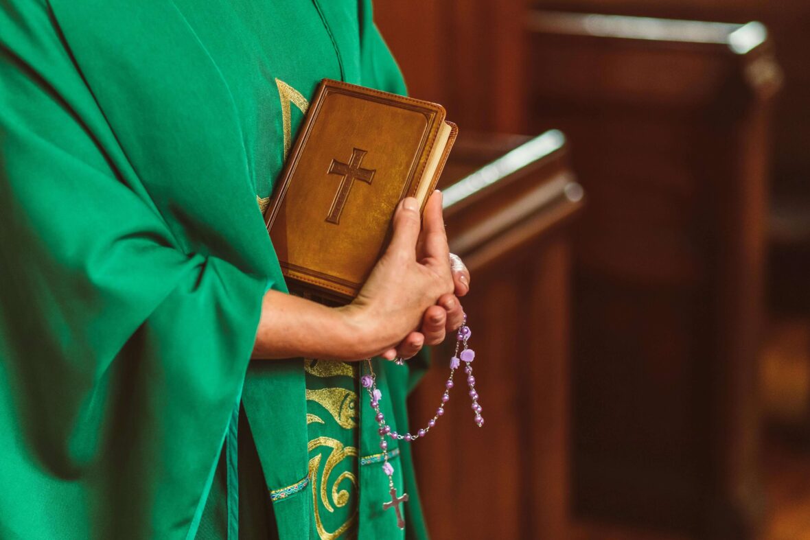 Priest carrying Bible and Rosary