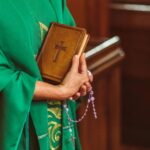 Priest carrying Bible and Rosary