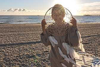 A young girl holding dreamer net on seashore