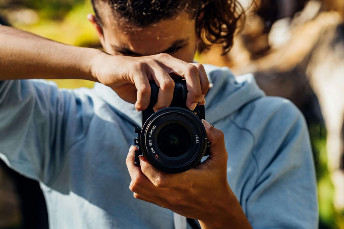 A Young Man Using A Black Dslr Camera