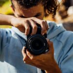 A Young Man Using A Black Dslr Camera