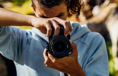A Young Man Using A Black Dslr Camera
